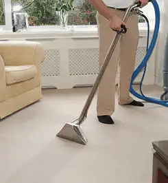 Professional carpet cleaner using a hot-water extraction wand and hose machine in a living room in Boulder, CO.
