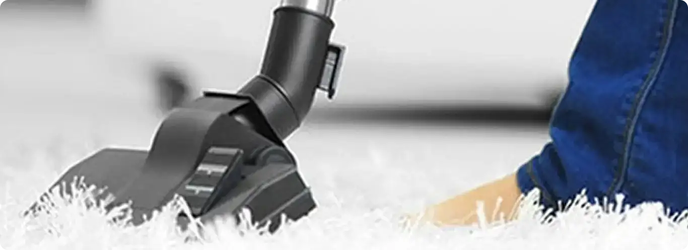 Close-up of a professional vacuuming a white carpet in Broomfield.