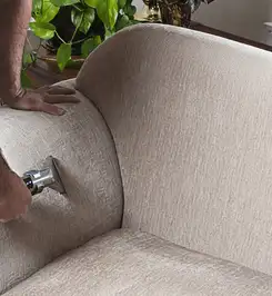 Professional upholstery cleaner deep-cleaning a fabric sofa with a handheld extraction tool and hose Boulder, CO.